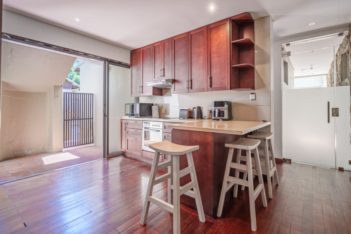 A functional kitchen featuring dark wood cabinetry, stone countertops, and a breakfast bar, with direct access to an outdoor patio area.