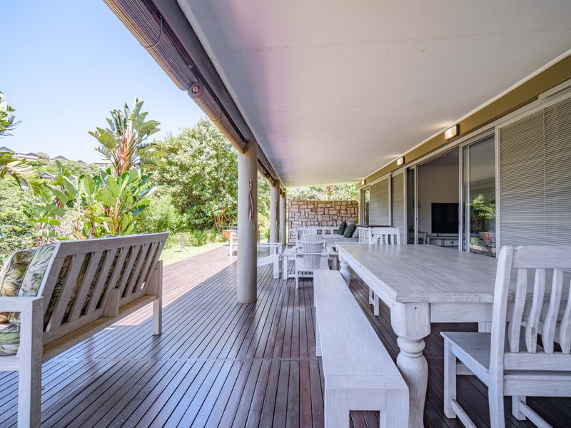 Spacious covered patio featuring timber decking, recessed lighting, and direct access to the garden through large sliding glass doors.