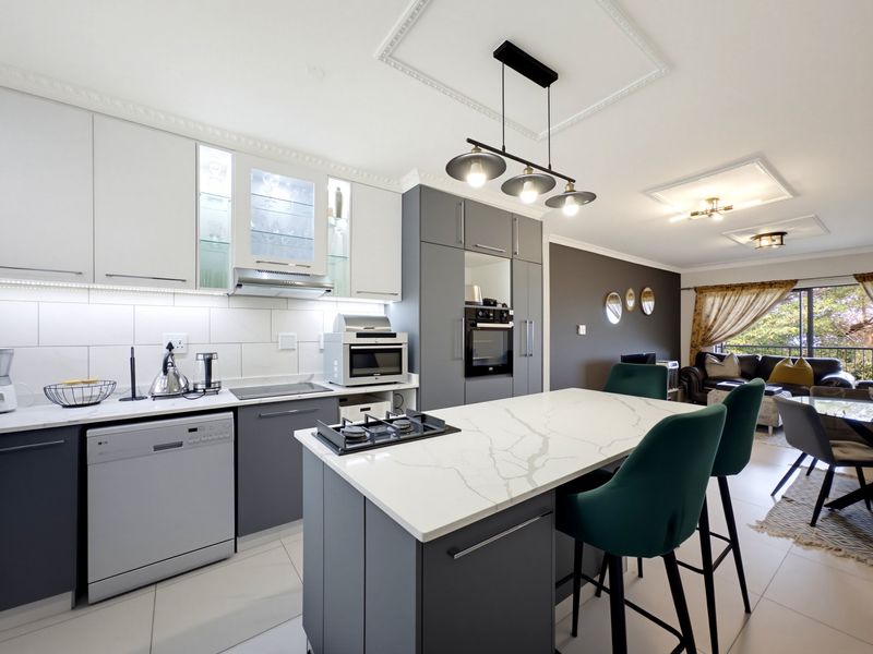 Modern open-plan kitchen featuring a central island with gas cooktop, sleek cabinetry, integrated appliances, and elegant pendant lighting, flowing into the living area.