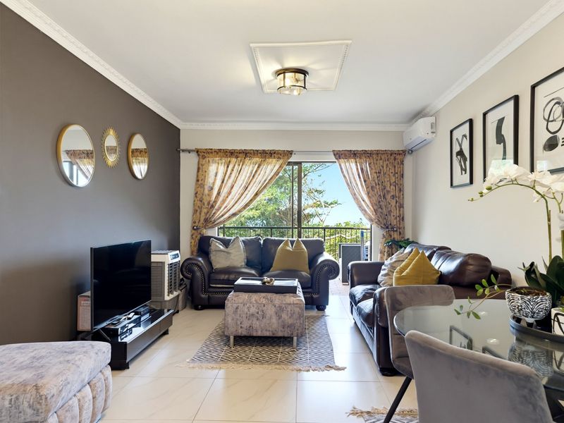 Open-plan living area featuring tiled floors, decorative ceiling molding, and a split-system air conditioner, with direct access to an outdoor balcony.