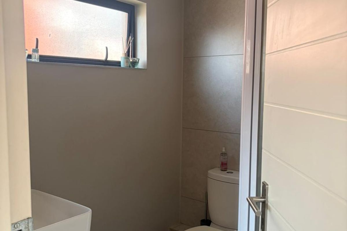 A modern bathroom featuring a vessel sink vanity, a toilet, and a shower enclosure with neutral wall and floor tiling.
