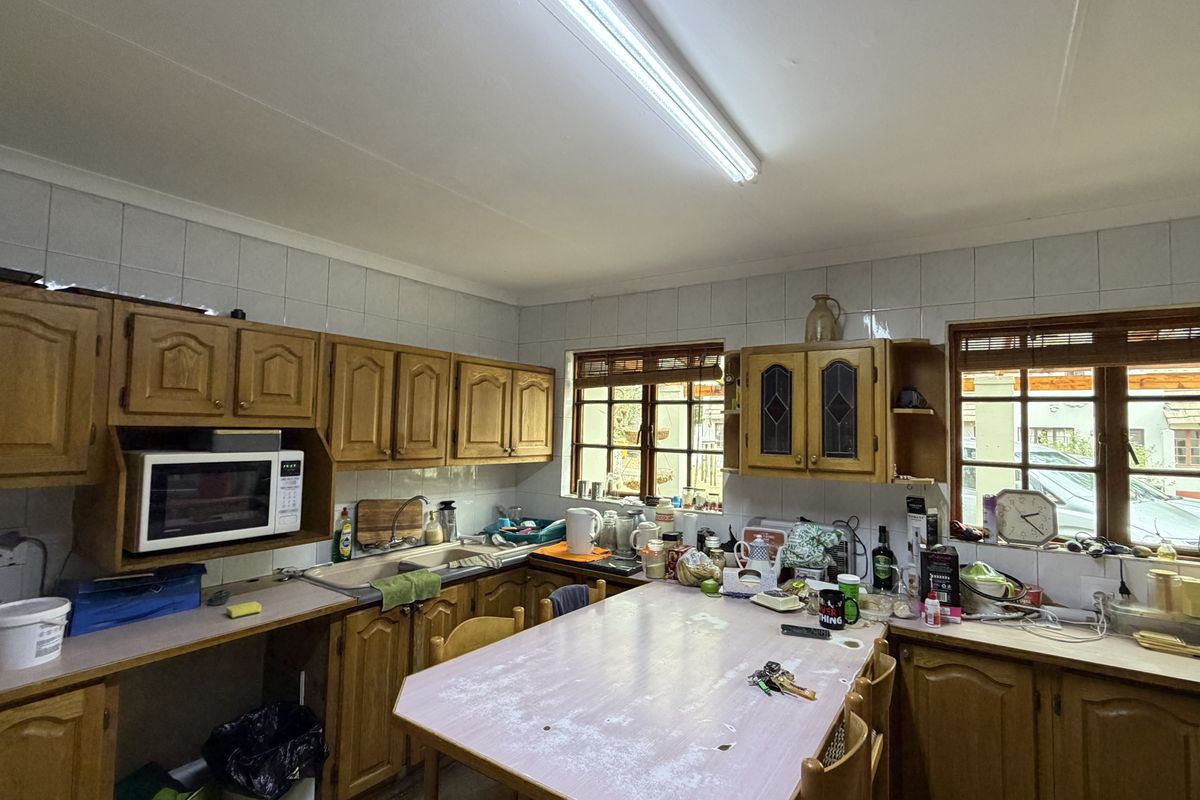 A functional kitchen featuring traditional wooden cabinetry, laminate countertops, and a tiled backsplash, offering a classic layout with ample storage space.