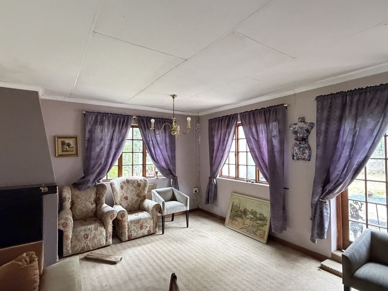 A living room featuring a fireplace, timber-framed windows, and access to the garden through a glass sliding door.