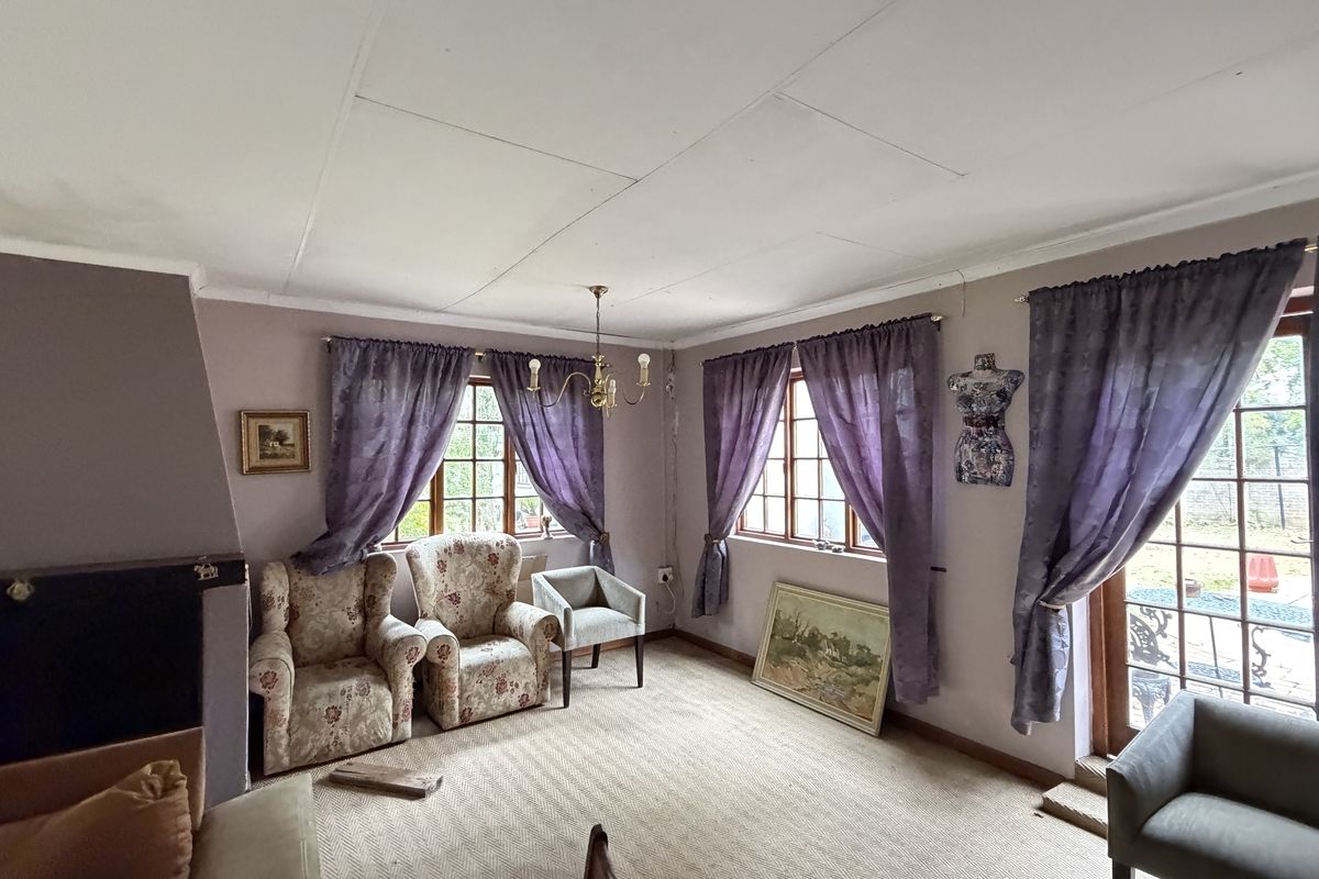 A living room featuring a fireplace, timber-framed windows, and access to the garden through a glass sliding door.
