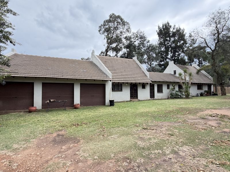Front view of a single-story house featuring a triple garage, traditional gabled roofline, and a large surrounding lawn area.