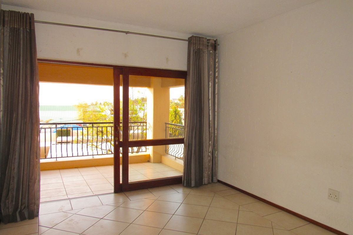 An empty living room featuring tiled flooring and a sliding glass door providing access to a private balcony.