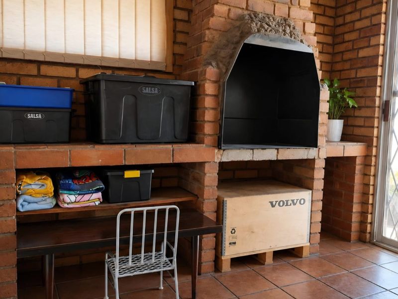 Covered patio area featuring a large built-in brick fireplace and tiled flooring, providing a functional space for outdoor entertaining.