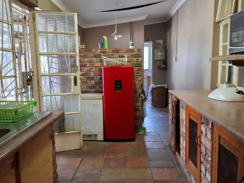 A rustic kitchen featuring brick cabinetry and island, tiled flooring, and a security gate, currently requiring ceiling repairs and cosmetic updates.