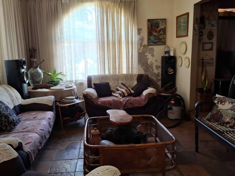 A living room featuring tiled flooring and a large window, currently showing significant wall surface deterioration requiring repair and redecoration.