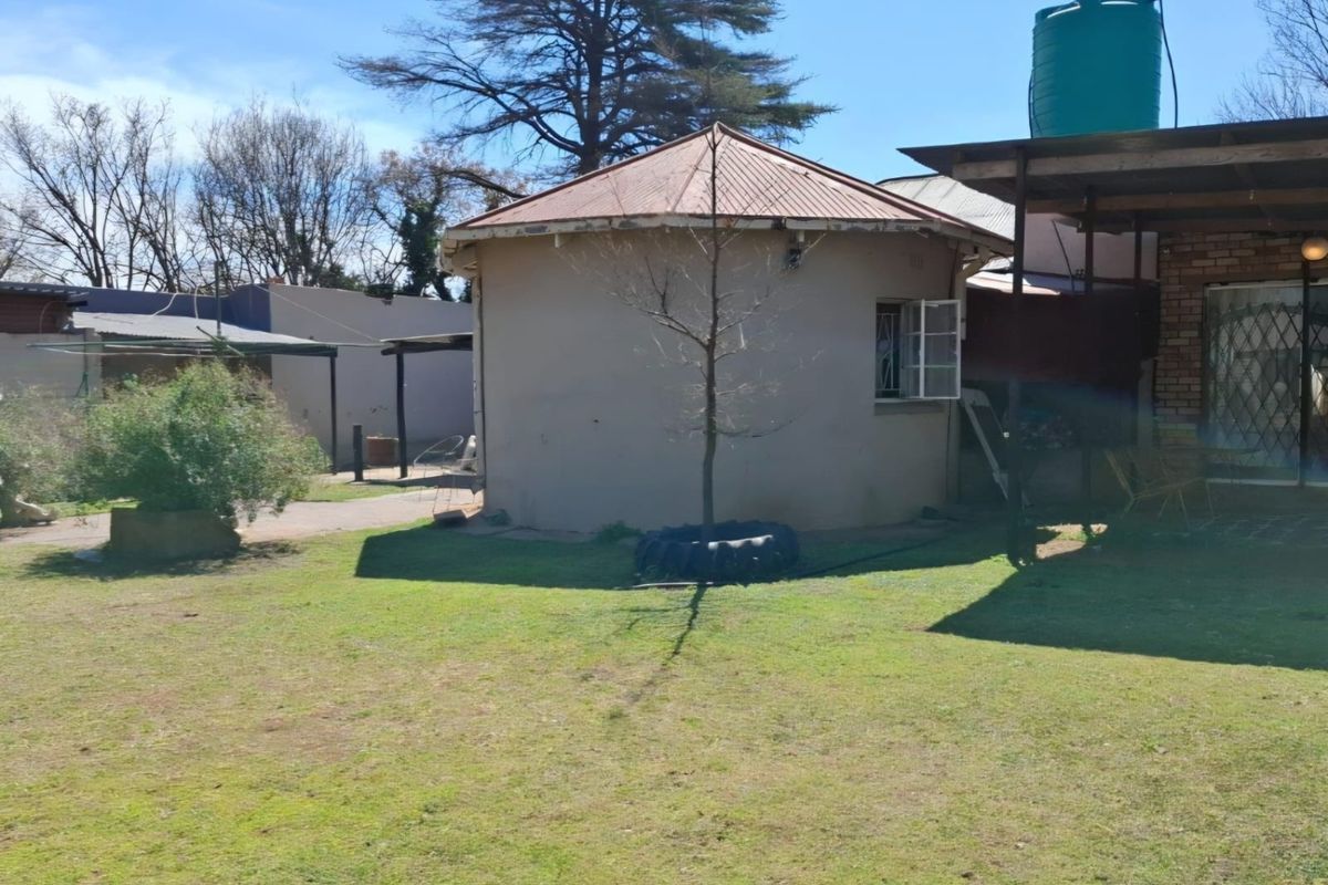 Rear view of the property featuring a circular structure, a water storage tank, and a covered patio area set within a garden.
