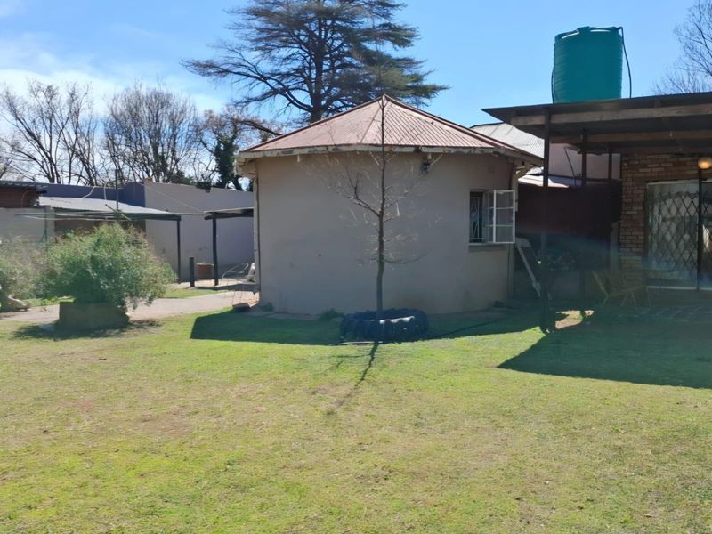 Rear view of the property featuring a circular structure, a water storage tank, and a covered patio area set within a garden.