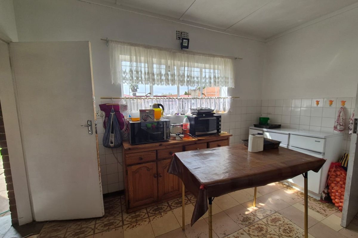 A dated kitchen featuring tiled flooring and a tiled backsplash, offering a functional layout ready for modern renovation and aesthetic updates.
