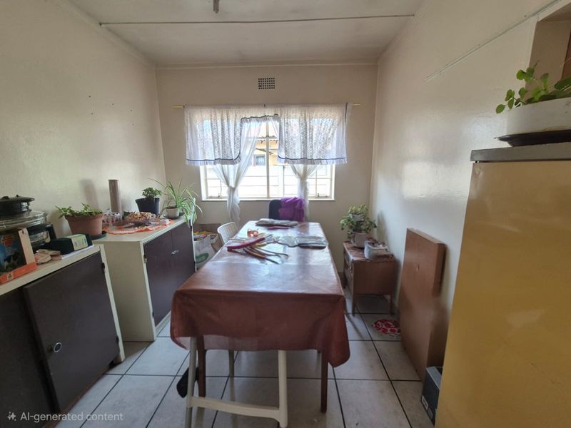 A simple dining area featuring tiled flooring and a window with security bars, offering a functional space ready for modernization.