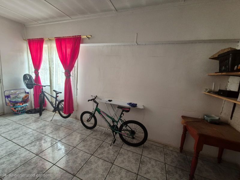 A living area featuring tiled flooring and a large window with curtain rods, requiring cosmetic updates to improve the overall aesthetic.