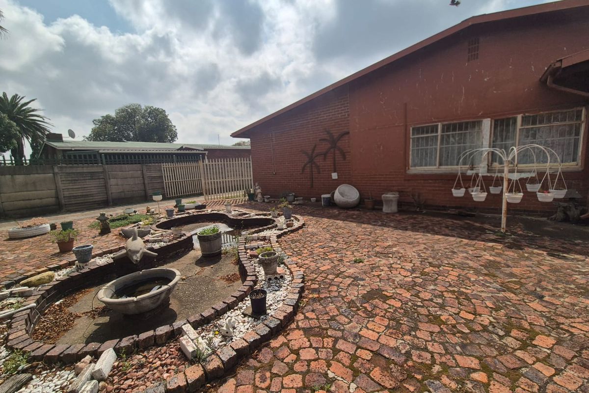 Rear exterior area featuring brick paving, a built-in pond feature, and a brick facade with large windows.