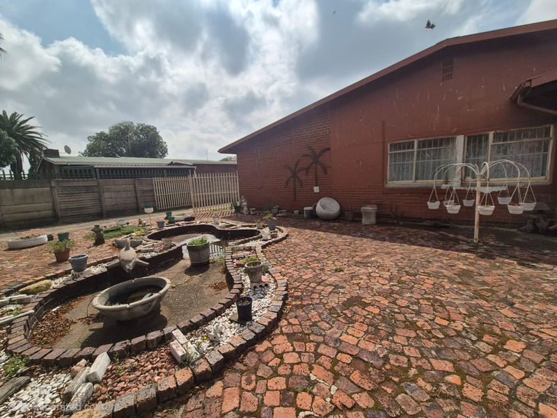 Rear exterior area featuring brick paving, a built-in pond feature, and a brick facade with large windows.