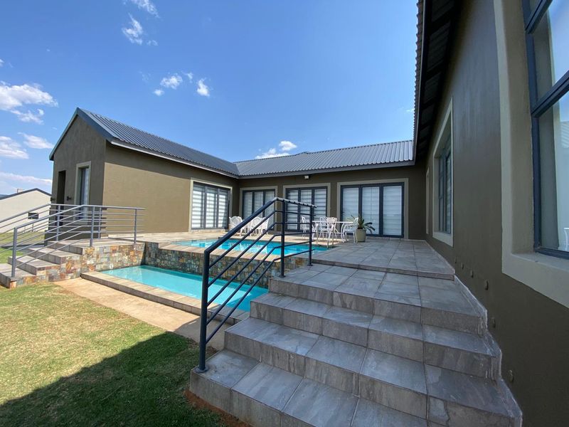 A well-maintained outdoor pool area featuring a tiled patio, tiered swimming pool, and direct access to the home via sliding glass doors.