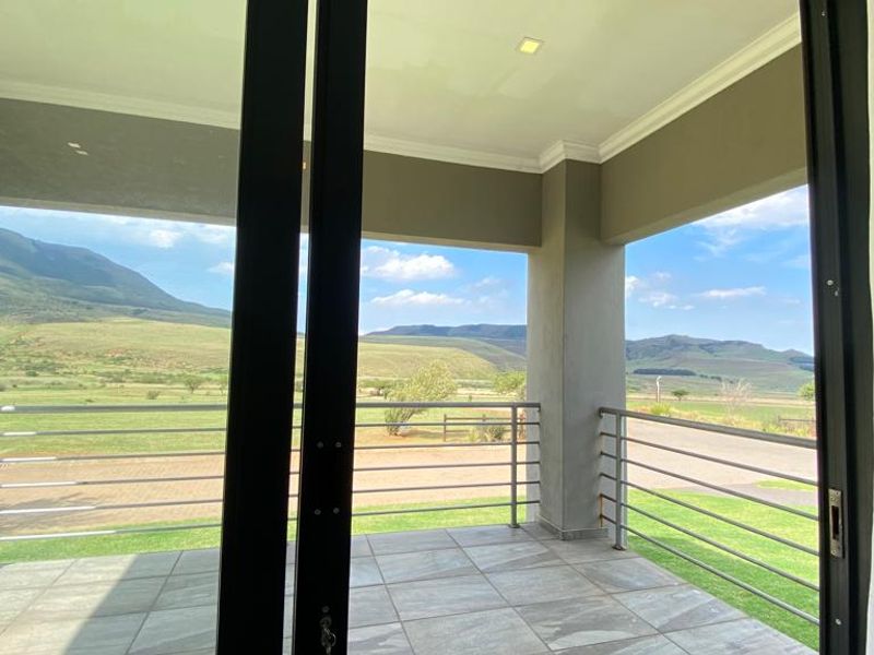 A covered balcony featuring tiled flooring, a modern metal balustrade, and expansive views of the surrounding landscape.