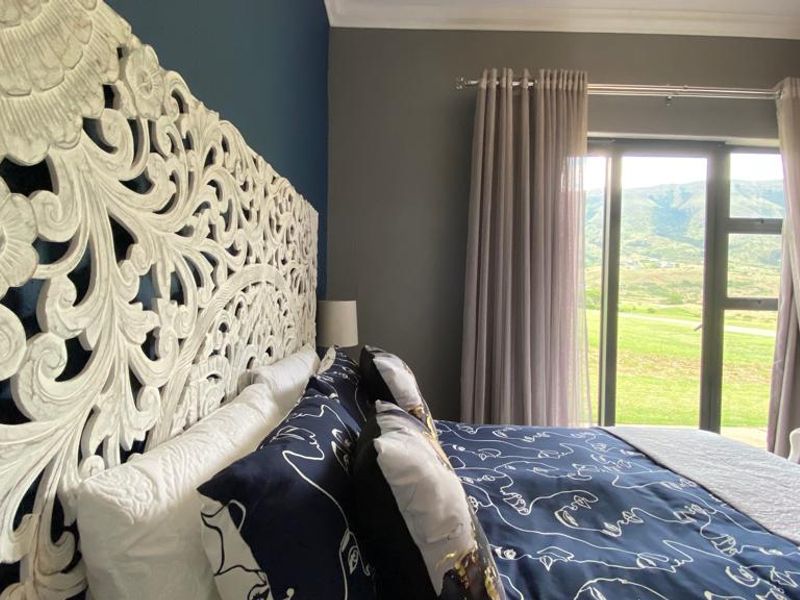 A well-maintained bedroom featuring dark accent walls, a large decorative headboard, and sliding glass doors providing natural light and scenic outdoor views.
