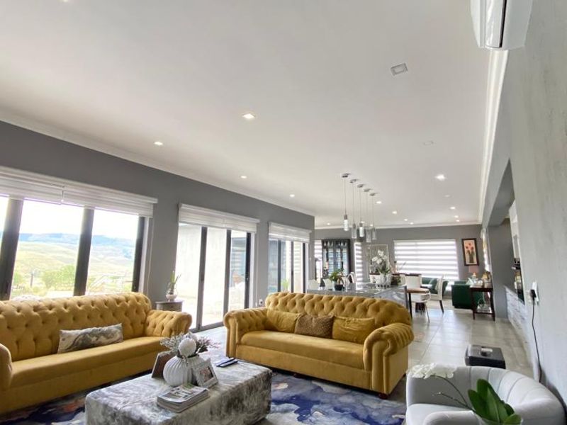 Spacious open-plan living and dining area featuring large format floor tiles, recessed lighting, and expansive sliding glass doors with scenic views.