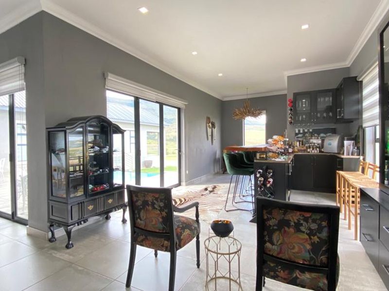 Spacious open-plan living and kitchen area featuring modern dark cabinetry, tiled floors, recessed lighting, and large sliding doors opening to the outdoor patio.