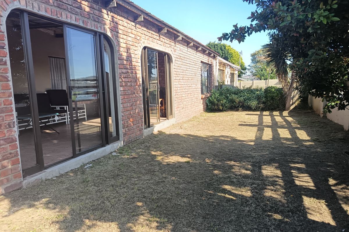 Rear view of the townhouse featuring an exposed brick facade, sliding glass doors providing indoor-outdoor flow, and a private garden area.