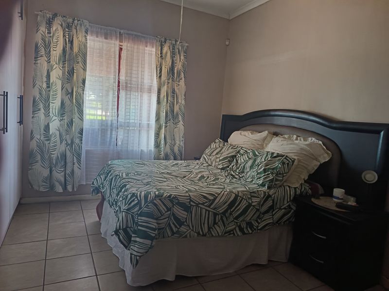 A functional bedroom featuring tiled flooring, built-in cupboards, and cove cornicing, offering a neutral base for potential interior updates.