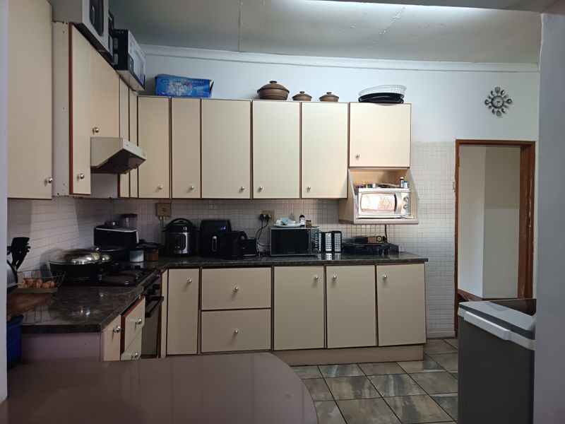 A functional kitchen featuring laminate cabinetry, granite countertops, tiled backsplash, and built-in cooking appliances, offering a practical layout with potential for modern updates.