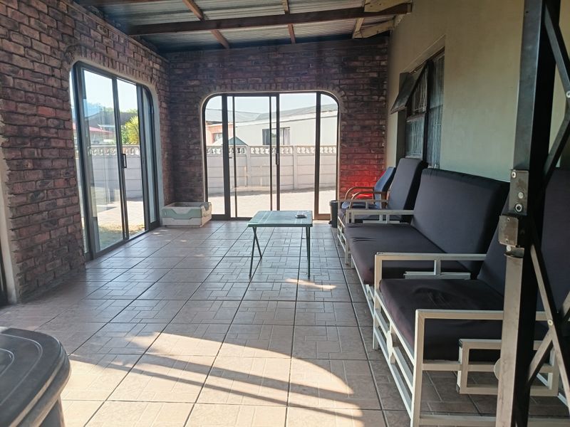Covered patio area featuring exposed brick walls, tiled flooring, and sliding glass doors providing access to the outdoor space.