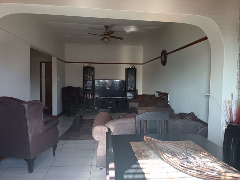 Open plan living and dining area featuring tiled flooring, a ceiling fan, and a distinctive architectural archway connecting the spaces.