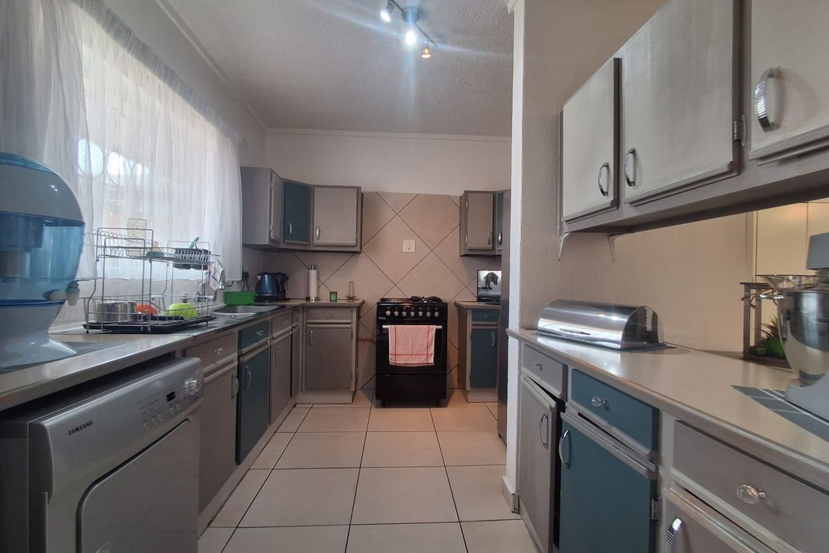 A functional kitchen featuring tiled flooring, ample built-in cabinetry, a tiled splashback, and a freestanding stove, offering a practical layout for daily cooking.