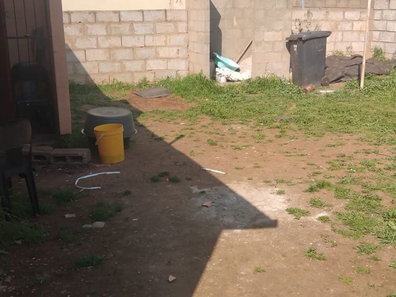 A rear yard area featuring an unfinished concrete block boundary wall and an unpaved ground surface, offering potential for landscaping and outdoor improvement.