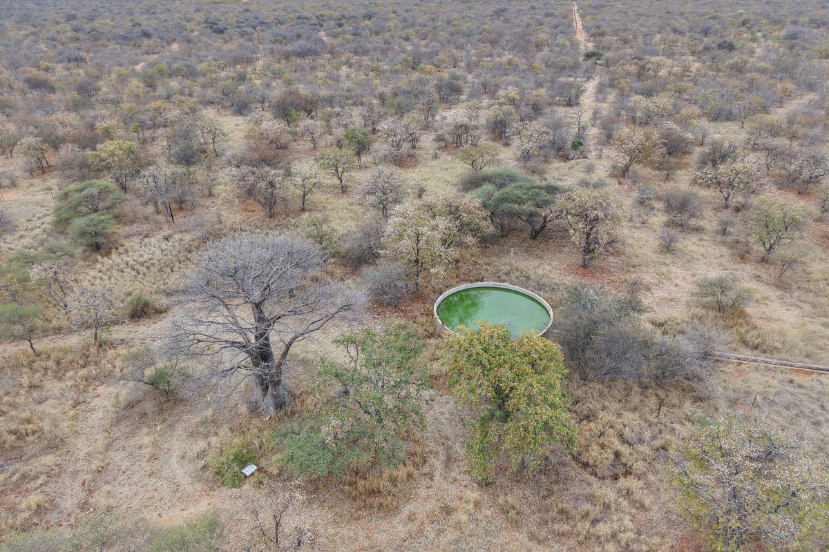 Aerial view of a rural farm property featuring a circular water reservoir set within a vast, dry bushveld landscape.