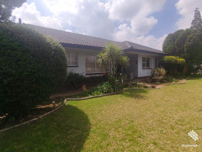 Front elevation of a single-story house featuring a tiled roof, security bars on windows, and a well-maintained front garden with a concrete pathway.