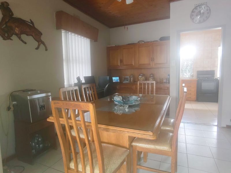 Dining room featuring tiled flooring, a timber tongue and groove ceiling with a ceiling fan, and built-in cabinetry, with an adjacent view into the kitchen.