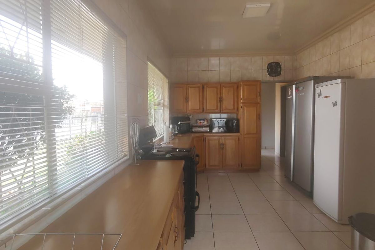 A functional kitchen featuring wooden cabinetry, tiled flooring, and tiled walls, offering ample storage and counter space.