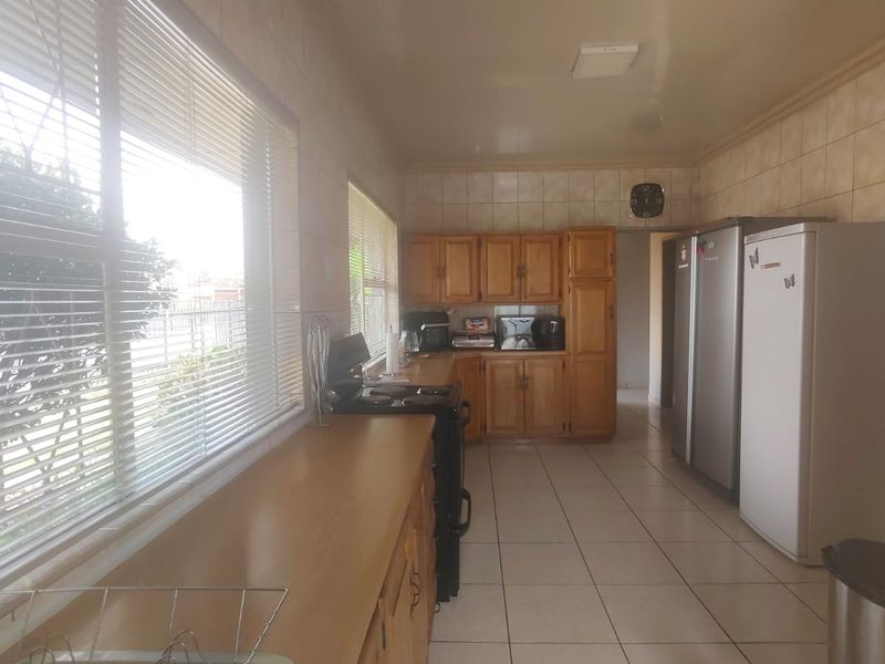 A functional kitchen featuring wooden cabinetry, tiled flooring, and tiled walls, offering ample storage and counter space.