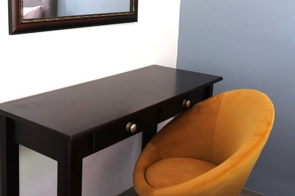 A bedroom corner featuring a desk area with a light switch on a painted accent wall.