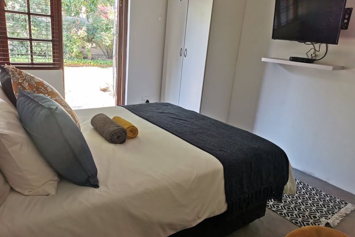 A bedroom featuring built-in wardrobes and french doors providing direct access to the garden area.