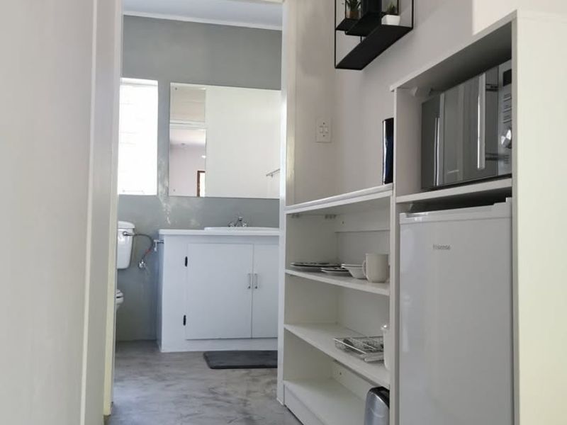A functional hallway area featuring concrete flooring, built-in shelving units, and a transom window, providing a direct view into the adjacent bathroom.