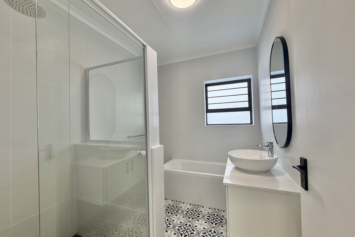 Modern bathroom featuring a glass-enclosed shower, a built-in bathtub, and a sleek vanity with a vessel sink and patterned floor tiles.