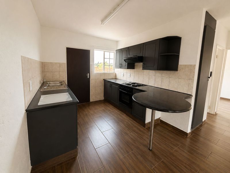Modern kitchen featuring dark cabinetry, black granite countertops, built-in oven with gas hob, extractor fan, and tiled flooring with a breakfast bar.