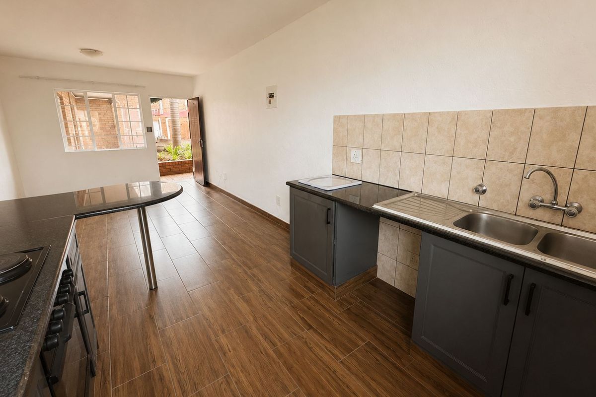 Modern kitchen featuring dark cabinetry, granite countertops, breakfast bar, and wood-look floor tiles, leading directly to an outdoor patio area.
