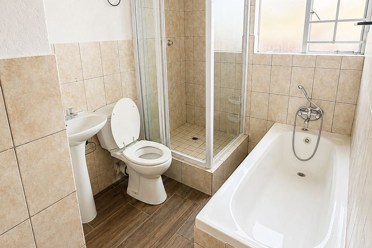 A clean, functional bathroom featuring a pedestal basin, toilet, separate shower enclosure, and a bathtub with tiled finishes throughout.