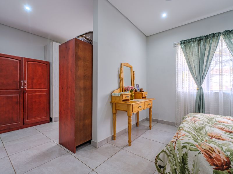 A well-maintained bedroom featuring neutral tiled flooring, recessed downlighting, and built-in cupboard storage.