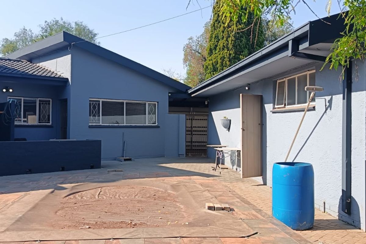 Rear exterior view of the property featuring a paved patio area and a swimming pool with a protective cover.