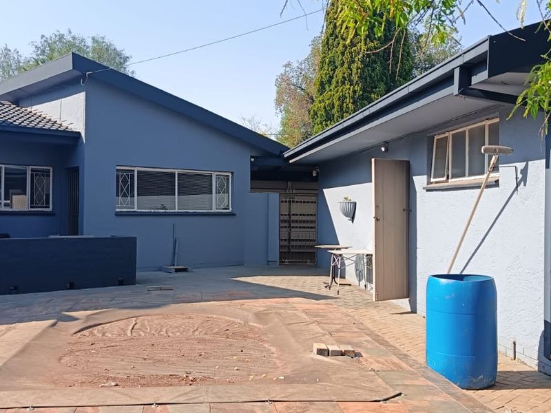 Rear exterior view of the property featuring a paved patio area and a swimming pool with a protective cover.