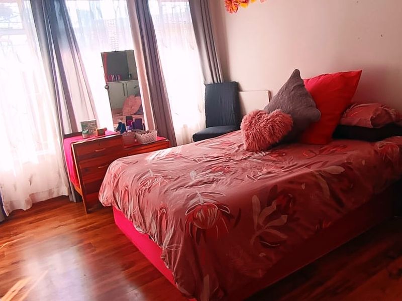 A bedroom featuring laminate flooring and a built-in wardrobe with large windows allowing natural light.