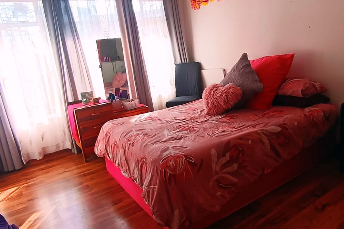 A bedroom featuring laminate flooring and a built-in wardrobe with large windows allowing natural light.