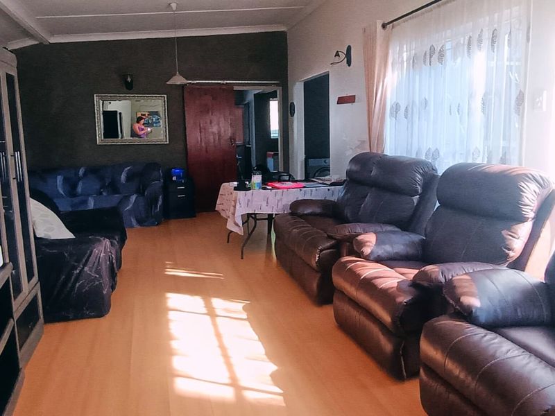 A spacious living room featuring laminate flooring and natural light, providing a comfortable area for relaxation and family gatherings.